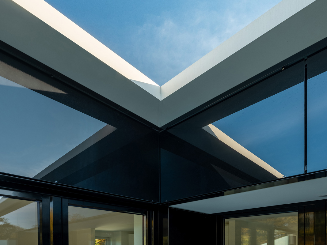 Innenecke des Penthouse aus einer Vorhangfassade aus schwarzem Glas mit spiegelung der Dachkanten.